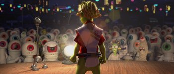 Movie still from “Planet 51” (2009), directed by Javier Abad – A person standing in front of a group of other people; Medium shot, Over the shoulder angle