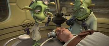 Movie still from “Planet 51” (2009), directed by Javier Abad – A cartoon of a man getting his head examined by two aliens; Medium shot, High angle
