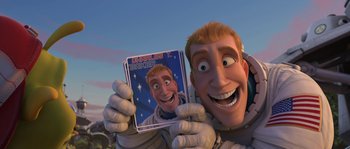Movie still from “Planet 51” (2009), directed by Javier Abad – An animated man holding a picture of himself in space; Medium shot, High angle