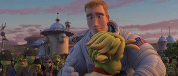 Movie still from “Planet 51” (2009), directed by Javier Abad – A man holding a bunch of bananas in his hands; Medium shot, Over the shoulder angle
