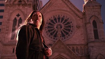 Movie still from “Planet Terror” (2007), directed by Robert Rodriguez – A woman standing in front of a building with a clock on it; Medium shot, Low angle