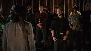 Movie still from “Planet Terror” (2007), directed by Robert Rodriguez – A group of men standing in front of a wall; Medium shot, Over the shoulder angle