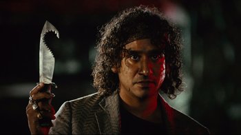 Movie still from “Planet Terror” (2007), directed by Robert Rodriguez – A person wearing a suit and tie; Close Up shot, Low angle