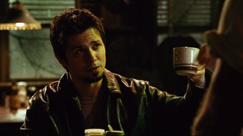 Movie still from “Planet Terror” (2007), directed by Robert Rodriguez – A man holding a coffee cup in a dark room; Close Up shot, Low angle