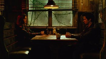 Movie still from “Planet Terror” (2007), directed by Robert Rodriguez – Two people sitting at a table in front of a window; Wide shot, Over the shoulder angle