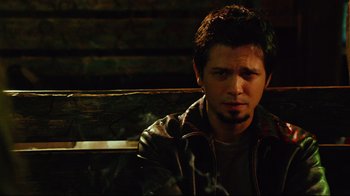 Movie still from “Planet Terror” (2007), directed by Robert Rodriguez – A man sitting on top of a wooden bench in the dark; Close Up shot, High angle
