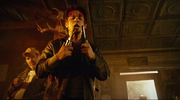 Movie still from “Planet Terror” (2007), directed by Robert Rodriguez – A man with a red bandage on his head holding a pair of tongs in his mouth; Medium shot, Low angle