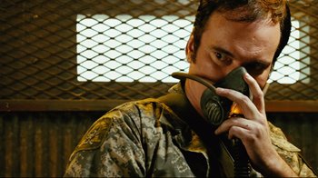 Movie still from “Planet Terror” (2007), directed by Robert Rodriguez – A man with a gas mask is holding a cell phone; Close Up shot, Low angle
