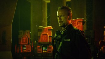 Movie still from “Planet Terror” (2007), directed by Robert Rodriguez – A man in a uniform standing next to a wall; Medium shot, Low angle