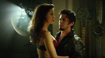 Movie still from “Planet Terror” (2007), directed by Robert Rodriguez – A man and a woman standing next to each other; Medium shot, Low angle