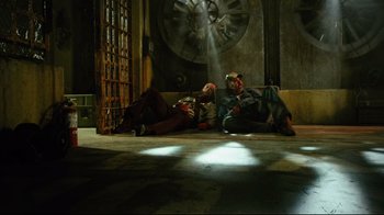 Movie still from “Planet Terror” (2007), directed by Robert Rodriguez – Two people sitting on the ground in a room; Wide shot, High angle