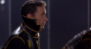 Movie still from “Planet of the Vampires” (1965), directed by Mario Bava – A man in a black and yellow suit looking to his left; Close Up shot, Over the shoulder angle