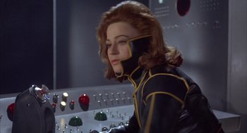Movie still from “Planet of the Vampires” (1965), directed by Mario Bava – A woman in a black and yellow suit is sitting in front of a computer; Medium shot, Low angle