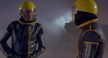 Movie still from “Planet of the Vampires” (1965), directed by Mario Bava – Two people in black and yellow suits and helmets; Medium shot, Over the shoulder angle