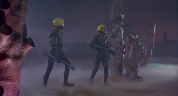 Movie still from “Planet of the Vampires” (1965), directed by Mario Bava – A couple of men in black suits and yellow helmets; Wide shot, Low angle