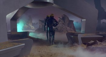 Movie still from “Planet of the Vampires” (1965), directed by Mario Bava – Two people in space suits are standing in the desert; Wide shot, High angle
