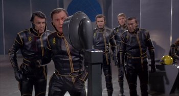 Movie still from “Planet of the Vampires” (1965), directed by Mario Bava – A group of men in black and yellow suits; Medium shot, Low angle