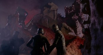 Movie still from “Planet of the Vampires” (1965), directed by Mario Bava – Two men in black suits standing on a rock formation; Wide shot, Low angle