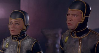 Movie still from “Planet of the Vampires” (1965), directed by Mario Bava – Two people in black and yellow suits standing next to each other; Close Up shot, Low angle