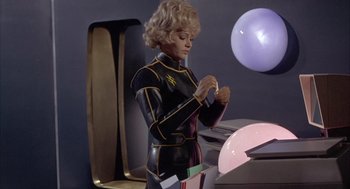 Movie still from “Planet of the Vampires” (1965), directed by Mario Bava – A woman in a black and yellow suit is looking down; Medium shot, Low angle