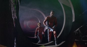 Movie still from “Planet of the Vampires” (1965), directed by Mario Bava – A man and a woman in red and grey costumes; Wide shot, Low angle