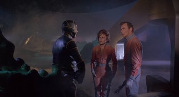 Movie still from “Planet of the Vampires” (1965), directed by Mario Bava – A group of people standing around in a room; Medium shot, Over the shoulder angle