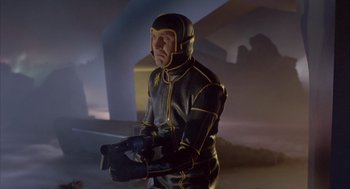 Movie still from “Planet of the Vampires” (1965), directed by Mario Bava – A man in a black and yellow costume holding a camera; Medium shot, Low angle