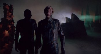 Movie still from “Planet of the Vampires” (1965), directed by Mario Bava – Two men in leather suits standing in front of a dark background; Medium shot, Low angle