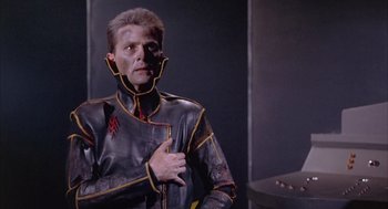 Movie still from “Planet of the Vampires” (1965), directed by Mario Bava – A man in a leather jacket standing next to a wall; Medium shot, Low angle