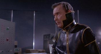 Movie still from “Planet of the Vampires” (1965), directed by Mario Bava – A man in a black and yellow jacket looking to his left; Medium shot, Over the shoulder angle