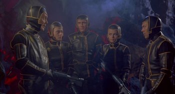 Movie still from “Planet of the Vampires” (1965), directed by Mario Bava – A group of people in black and yellow suits holding guns; Medium shot, High angle