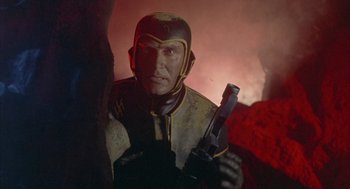 Movie still from “Planet of the Vampires” (1965), directed by Mario Bava – A man in a yellow and black outfit holding a gun; Medium shot, Low angle