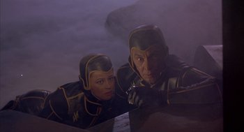 Movie still from “Planet of the Vampires” (1965), directed by Mario Bava – A couple of people that are standing in a room; Medium shot, High angle