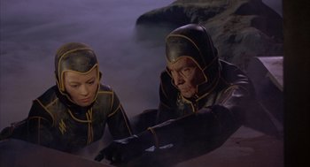 Movie still from “Planet of the Vampires” (1965), directed by Mario Bava – A man and a woman dressed in black and yellow; Medium shot, High angle