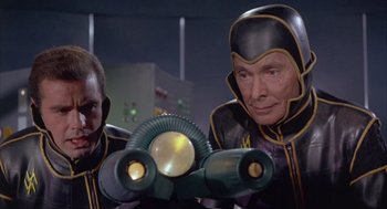 Movie still from “Planet of the Vampires” (1965), directed by Mario Bava – Two men in black and yellow suits looking through a pair of binoculars; Medium shot, Low angle