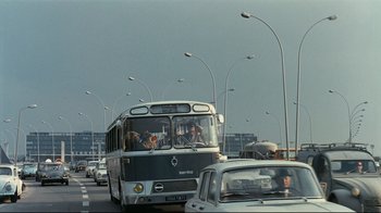 Movie still from “Playtime” (1967), directed by Jacques Tati – A city bus driving down a busy street; Extreme Wide shot, Low angle
