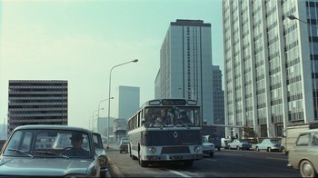 Movie still from “Playtime” (1967), directed by Jacques Tati – A bus is driving down a busy city street; Extreme Wide shot, Low angle