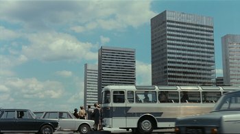 Movie still from “Playtime” (1967), directed by Jacques Tati – A group of people standing next to a bus on the street; Extreme Wide shot, Low angle