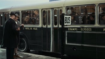 Movie still from “Playtime” (1967), directed by Jacques Tati – A group of people riding on the side of a bus; Wide shot, Low angle