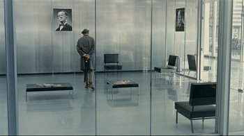 Movie still from “Playtime” (1967), directed by Jacques Tati – A man standing in front of a glass wall; Wide shot, High angle