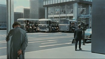 Movie still from “Playtime” (1967), directed by Jacques Tati – A group of buses parked in front of a building; Wide shot, High angle