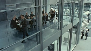 Movie still from “Playtime” (1967), directed by Jacques Tati – A group of people sitting at tables in an office building; Wide shot, High angle