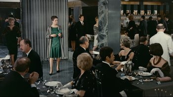 Movie still from “Playtime” (1967), directed by Jacques Tati – A group of people sitting at tables in a room; Wide shot, Over the shoulder angle