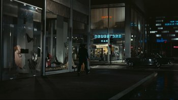 Movie still from “Playtime” (1967), directed by Jacques Tati – Two people walking in front of a building at night; Extreme Wide shot, High angle