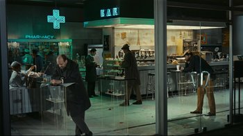 Movie still from “Playtime” (1967), directed by Jacques Tati – A group of people standing around a bar; Wide shot, High angle