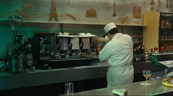 Movie still from “Playtime” (1967), directed by Jacques Tati – A man working in a restaurant kitchen making coffee; Wide shot, High angle