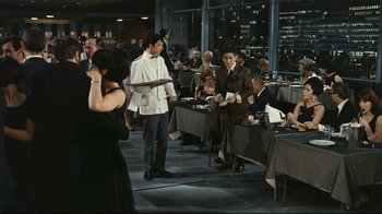 Movie still from “Playtime” (1967), directed by Jacques Tati – A group of people sitting at tables in a restaurant; Wide shot, High angle