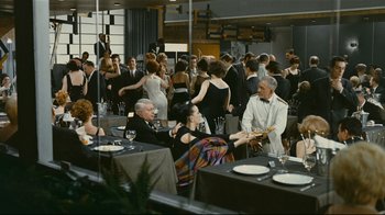 Movie still from “Playtime” (1967), directed by Jacques Tati – A group of people sitting at tables in a room; Wide shot, High angle