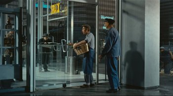 Movie still from “Playtime” (1967), directed by Jacques Tati – Two men standing in front of a glass door; Wide shot, High angle