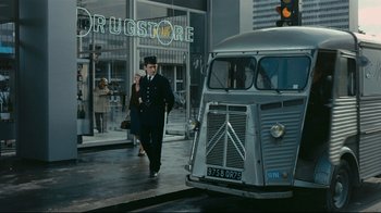 Movie still from “Playtime” (1967), directed by Jacques Tati – A man walking down the street in front of a bus; Wide shot, Over the shoulder angle